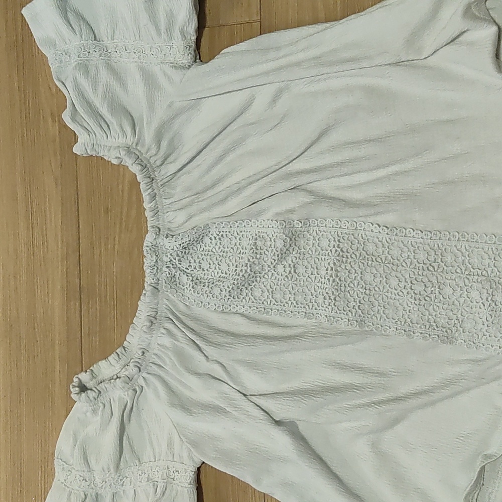 White women's blouse, with floral design down the middle and on sleeves.